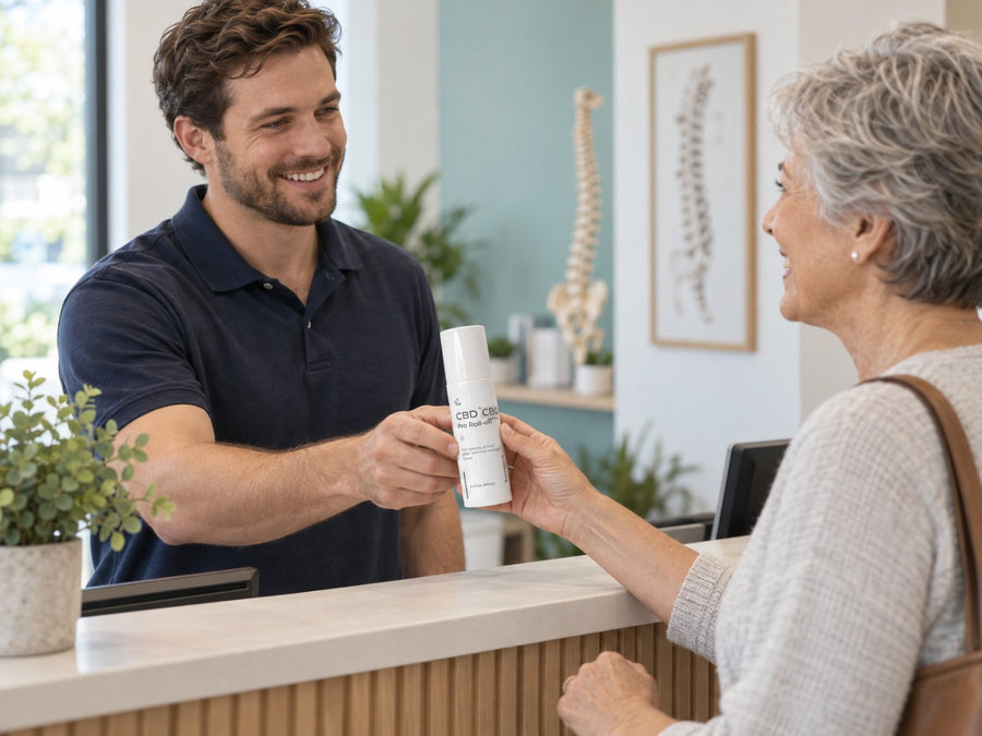 A chiropractor handing a Pro Roll-On bottle to a patient at the front desk
