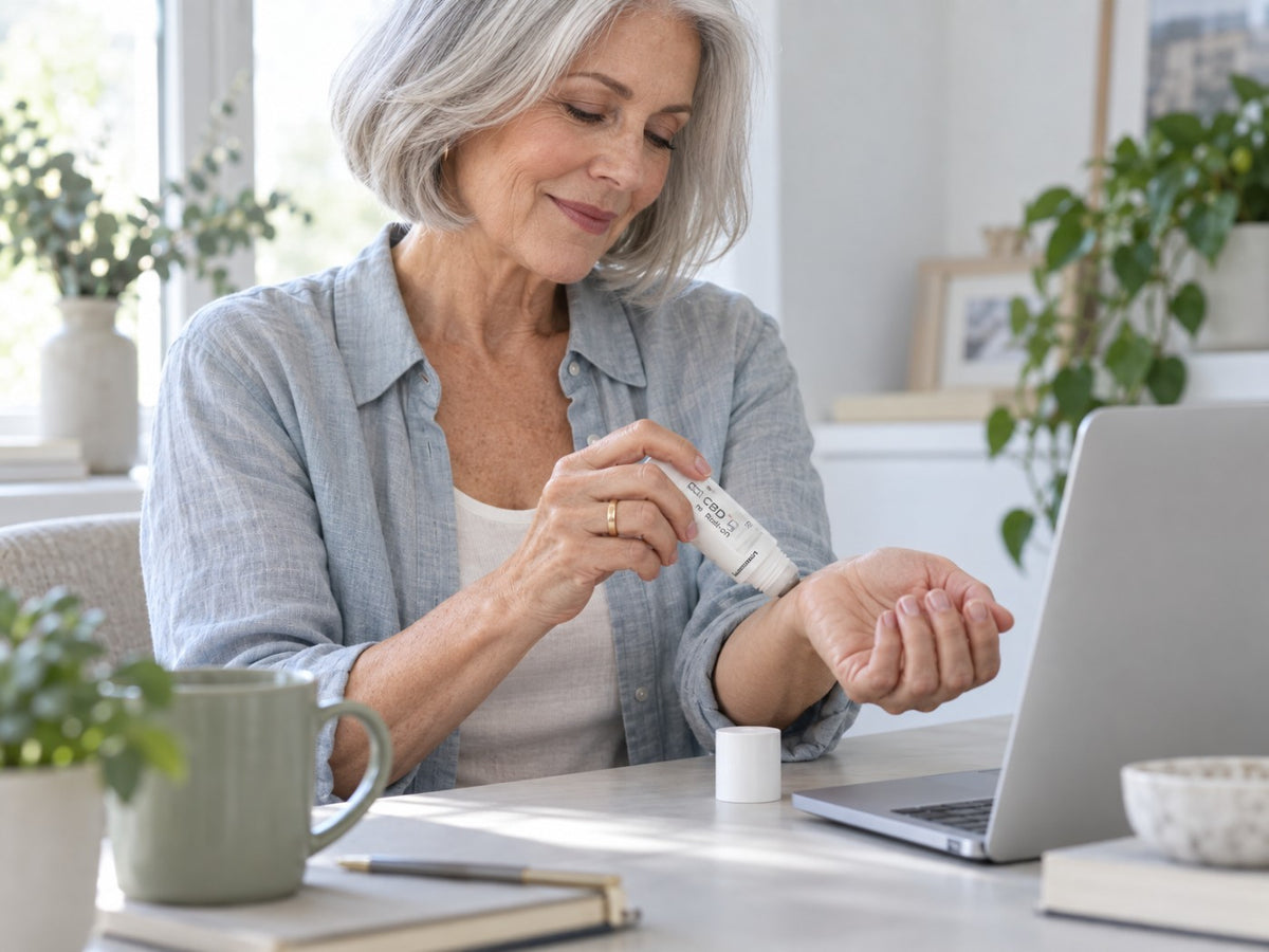 A woman in her sixties rolling Pro Roll-On onto her wrist at a desk