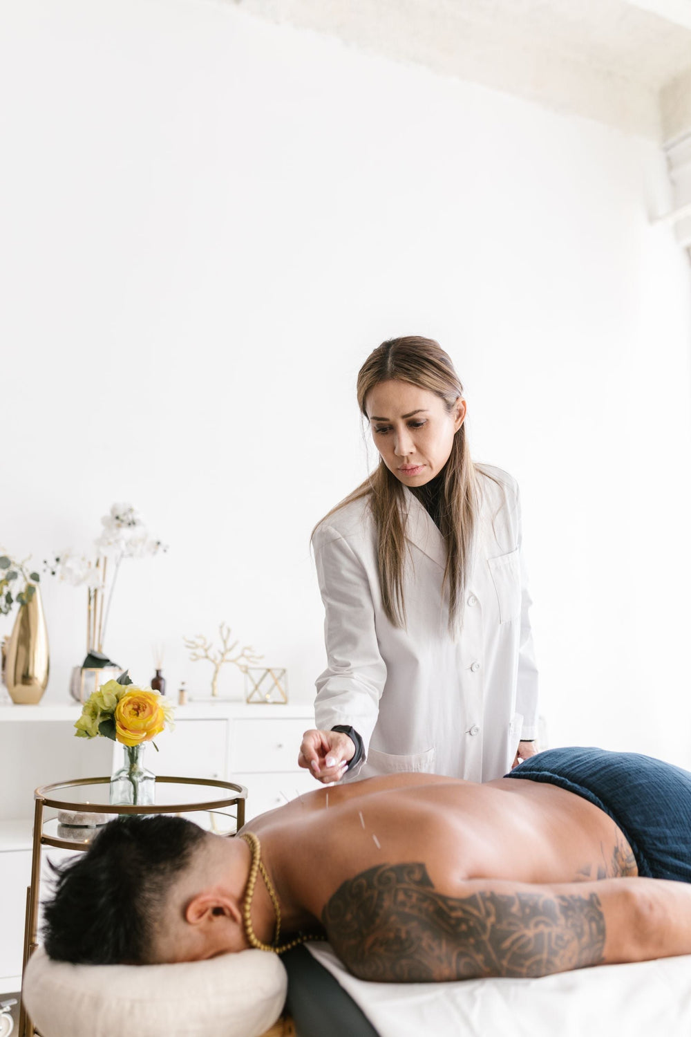 Acupuncturist placing needles during a session in a bright treatment room